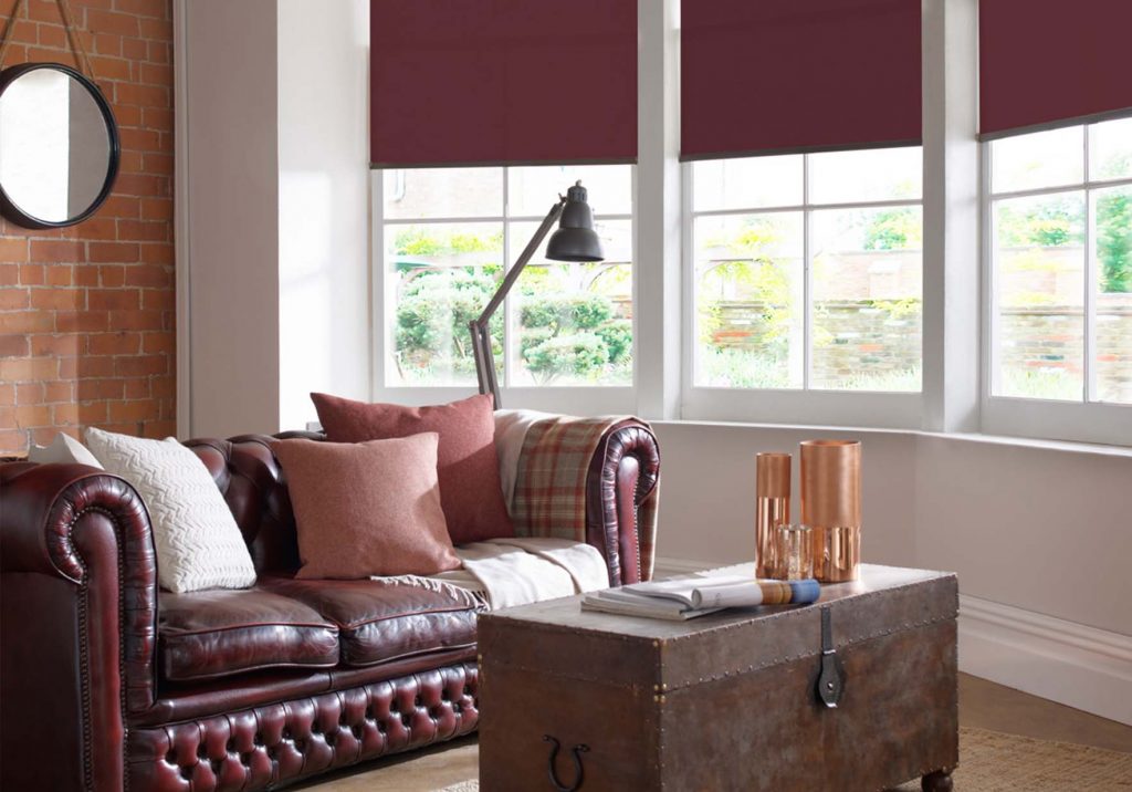 red roller blinds in angled bay window